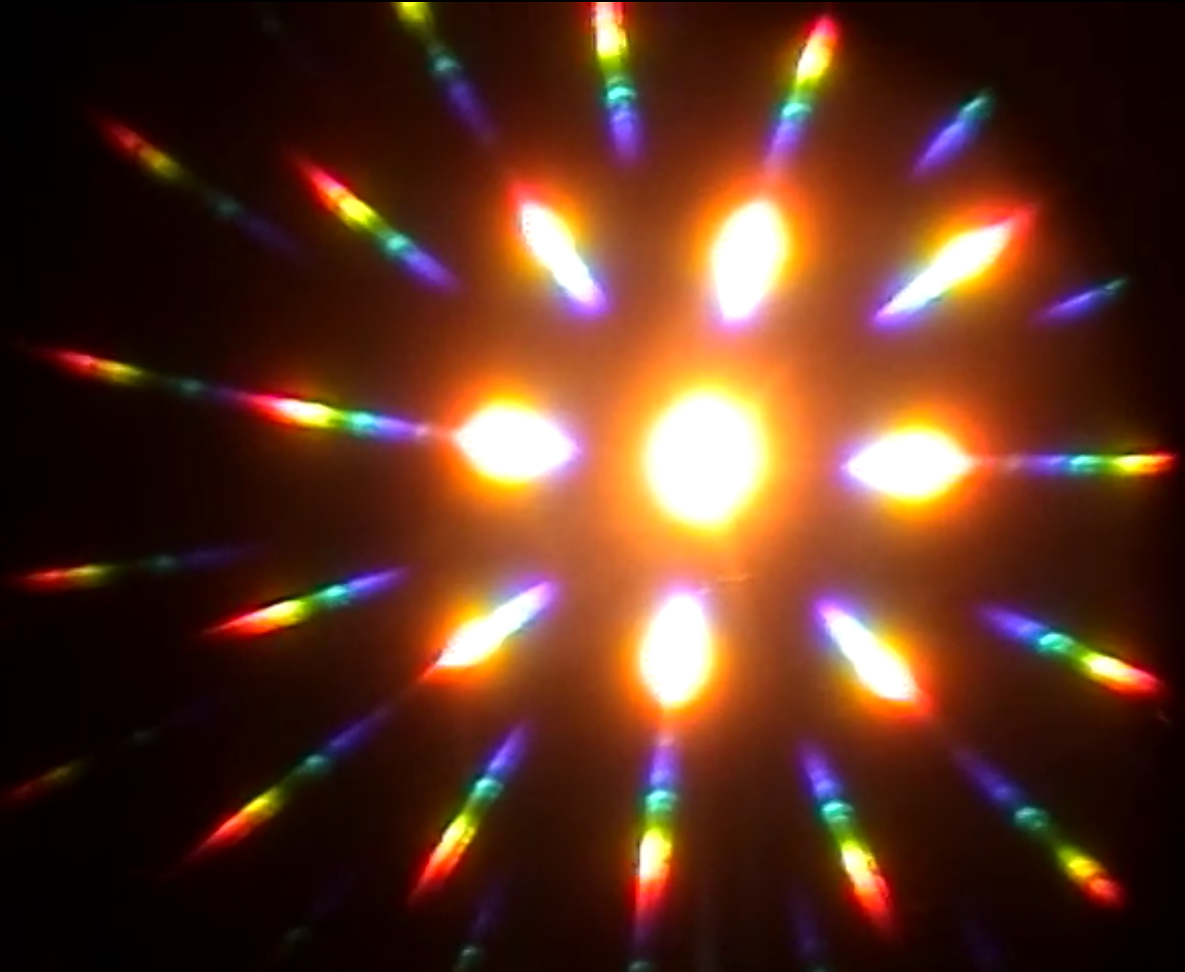 A glowing yellow orb in the middle of the photograph has concentric patterns of rainbow light shooting in every direction.